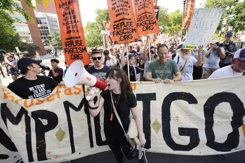Activists carrying signs march to the White House to protest Trump's federal takeover of policing of the District of Columbia, Saturday, Aug. 16, 2025, in Washington