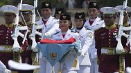 La abanderada Bianca Alessia Christabella Lantang, en el centro, lleva una bandera indonesia en una bandeja para izarla durante una ceremonia para conmemorar el día