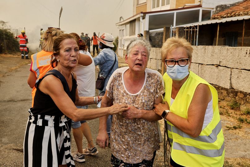 Una anciana es evacuada durante un incendio forestal en Veiga das Meas, al noroeste de España, el sábado 16 de agosto de 2025.
