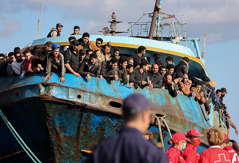 Migrants look out of a fishing boat docked at the port of Palaiochora in southeastern Crete, 22 November, 2022
