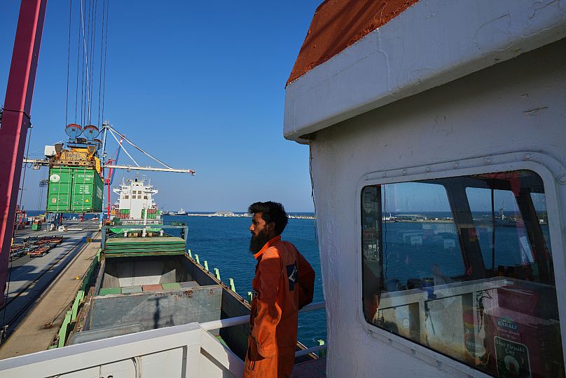 Jalal Uddin, electrical and technology officer aboard a Panamanian-flagged ship watches as containers filled with aid are loaded at the port in Limassol, 18 August, 2025