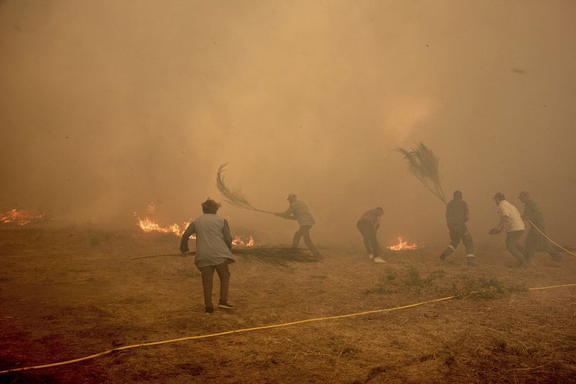 Residents battle a fire advancing toward Rebordondo village, near Ourense, in northwestern Spain, on Monday, Aug. 18, 2025