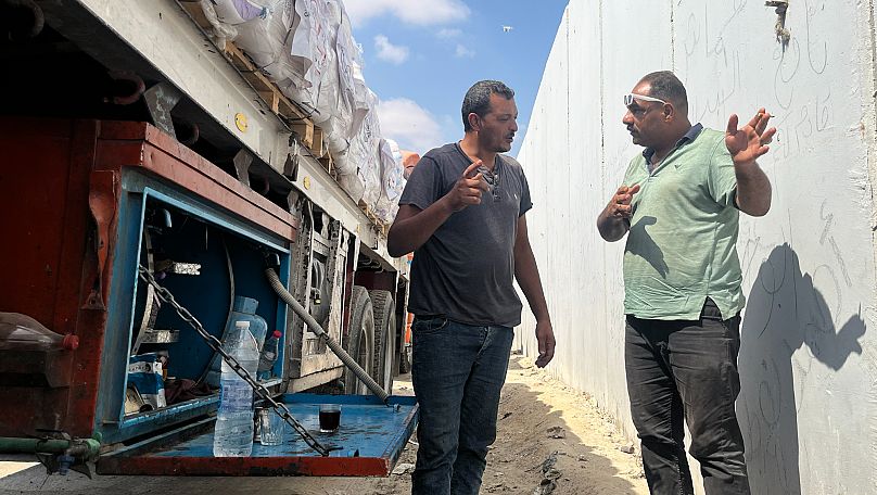 Des chauffeurs de camions d'aide humanitaire discutent autour d'un café au poste-frontière de Rafah, en Égypte, le 18 août 2025