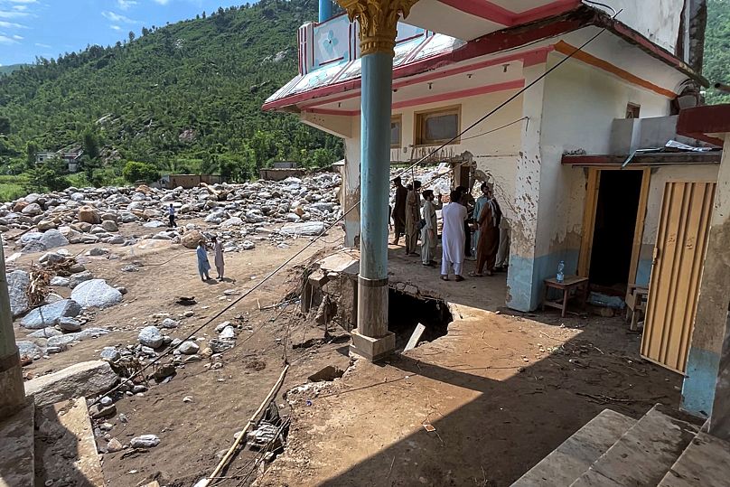 Residenti osservano una casa danneggiata dopo che le inondazioni nella zona di Qadar Nagar nel nord del Pakistan (18 agosto 2025)