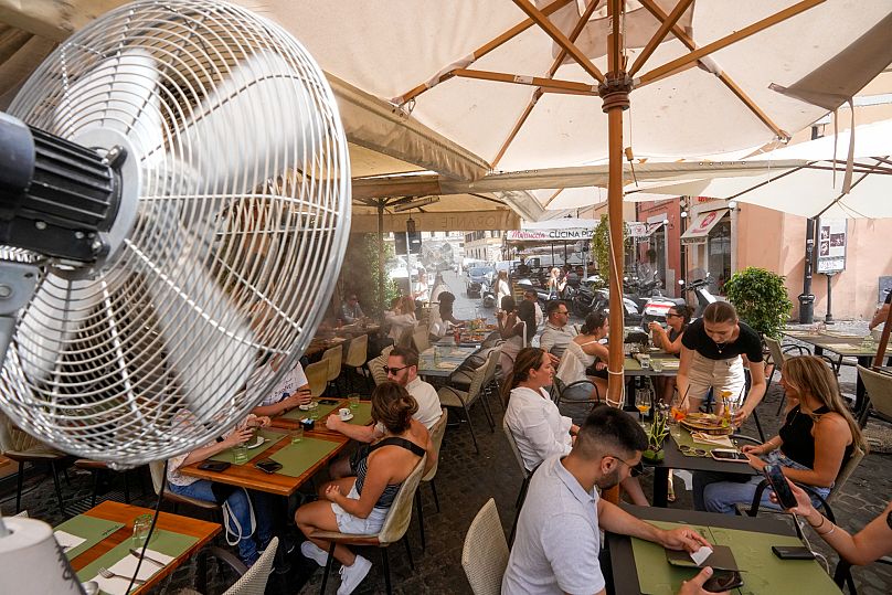 Una escena típica en los países mediterráneos: comer al aire libre mientras un ventilador rocía agua para refrescar a los comensales.