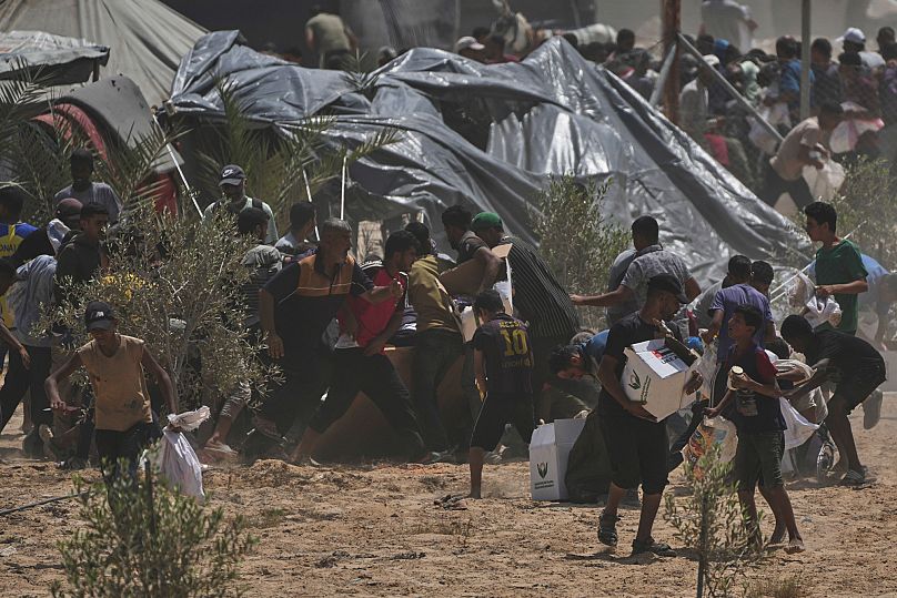 Palestinians rush to collect humanitarian aid packages from the United Arab Emirates, airdropped by parachutes into Deir al-Balah, in the central Gaza Strip, Aug. 19, 2025.