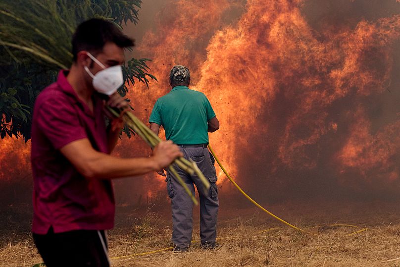 Residents battle a wildfire advancing toward Rebordondo village, near Ourense, in northwestern Spain, on Monday, Aug. 18, 2025.