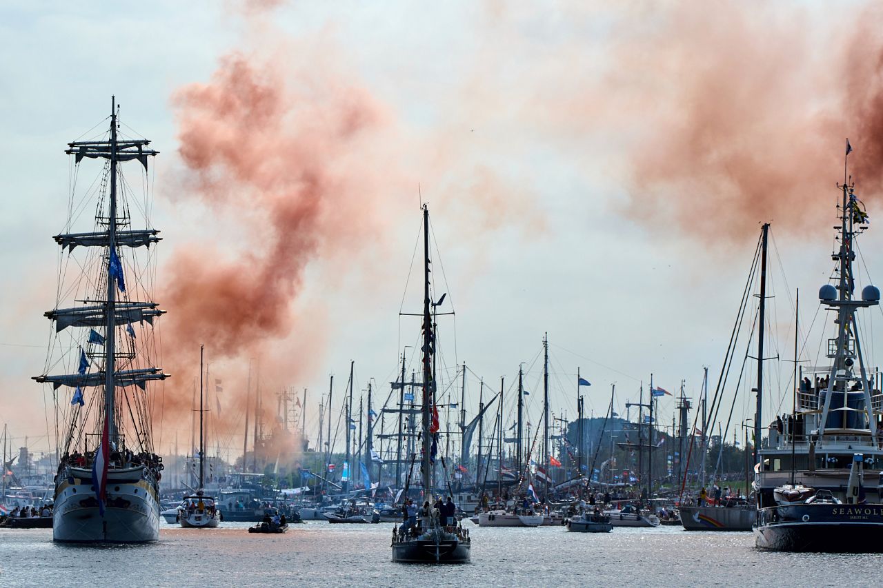 Orange smoke signals the start of the parade of hundreds of tall ships sailing into the Dutch capital's harbor - 20 August 2025