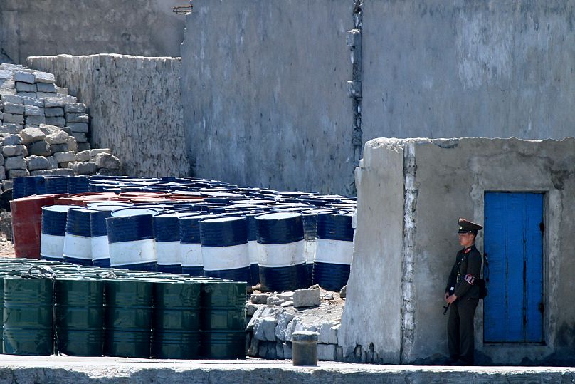 A North Korean solder stands guard near oil barrels stocked up near the river bank in the town of Sinuiju, 8 May, 2016