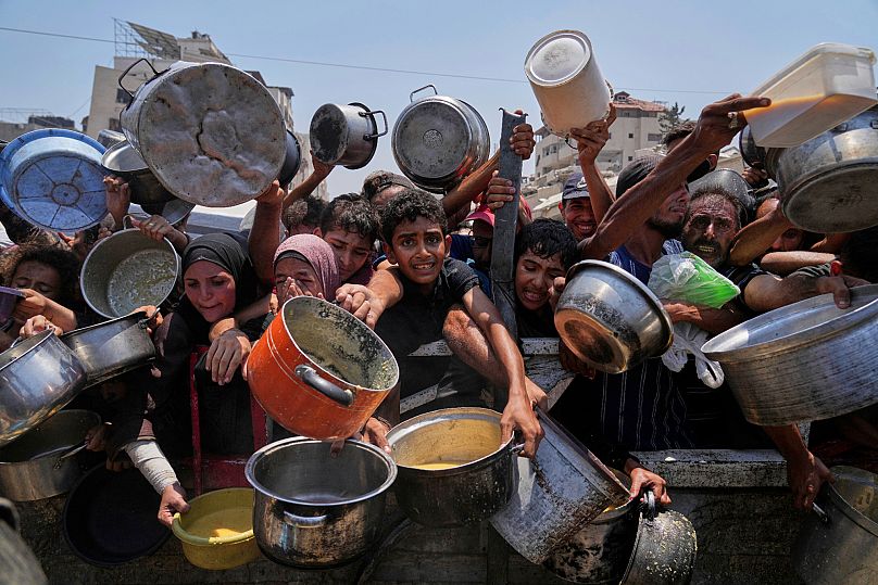 Palestinos luchan por conseguir alimentos donados en una cocina comunitaria en Gaza, norte de la Franja de Gaza, 26 de julio de 2025.