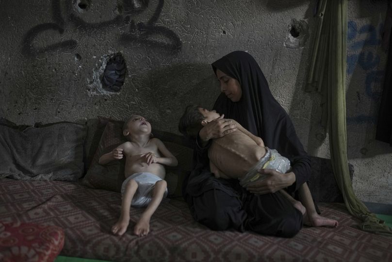 سماح مطر مع طفليها يوسف (6 سنوات) وأمير (4 سنوات) المصابان بسوء تغذية وشلل دماغي، في مدرسة تابعة للأمم المتحدة بمدينة غزة، 26 يوليو 2025.