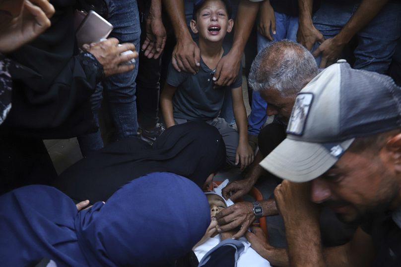 Palestinian relatives mourn over the body of 13-year-old Karim Qdeih, who was killed along with others in overnight Israeli strikes in Khan Younis, Saturday, Aug. 23, 2025