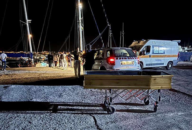 Nesta foto fornecida pela RESQSHIP, vê-se um caixão no cais da ilha siciliana de Lampedusa, no início da manhã de sábado, 23 de agosto de 2025.