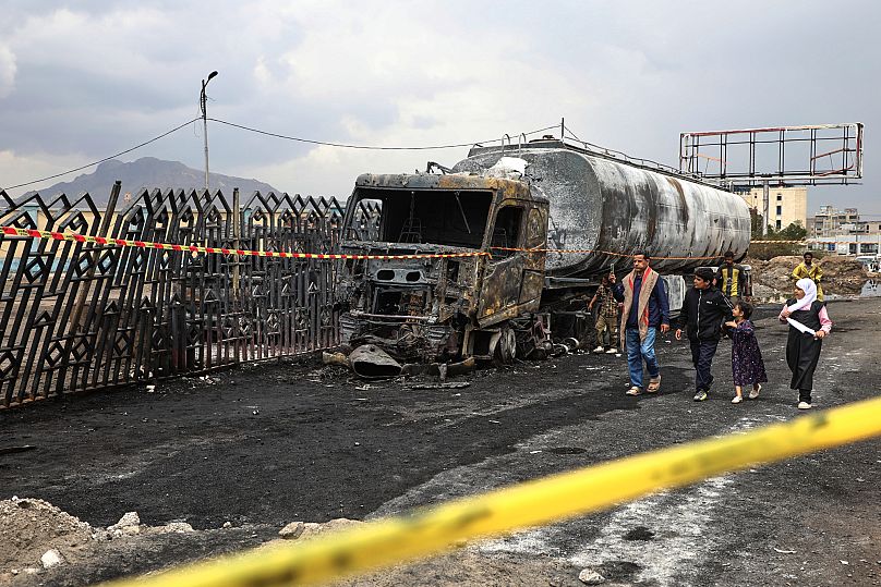 Sana’da İsrail hava saldırılarında imha edilen bir akaryakıt tankerinin enkazının yanından insanlar geçiyor, 25 Ağustos 2025