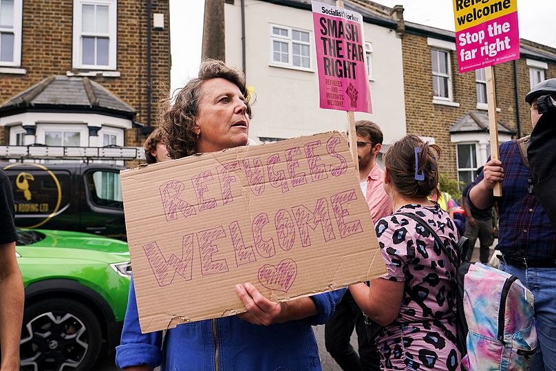 A demonstrator holds a placard as she leaves a protest outside the Bell Hotel in Epping, 27 July, 2025