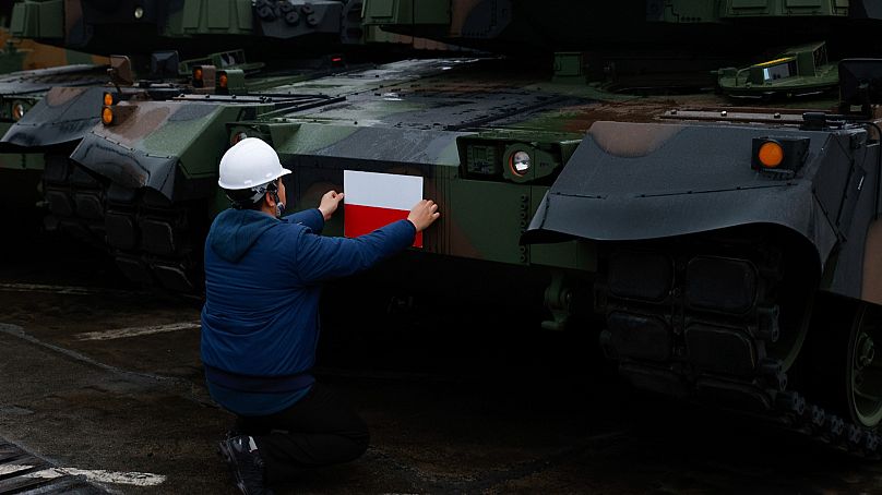 A worker puts a Polish flag on the South Korean Black Panther K2 tank in the Polish Navy port of Gdynia, Poland, 6 Dec, 2022.