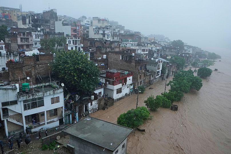 People watch a swelling River Tawi from the roof of their houses in Jammu, 26 August, 2025