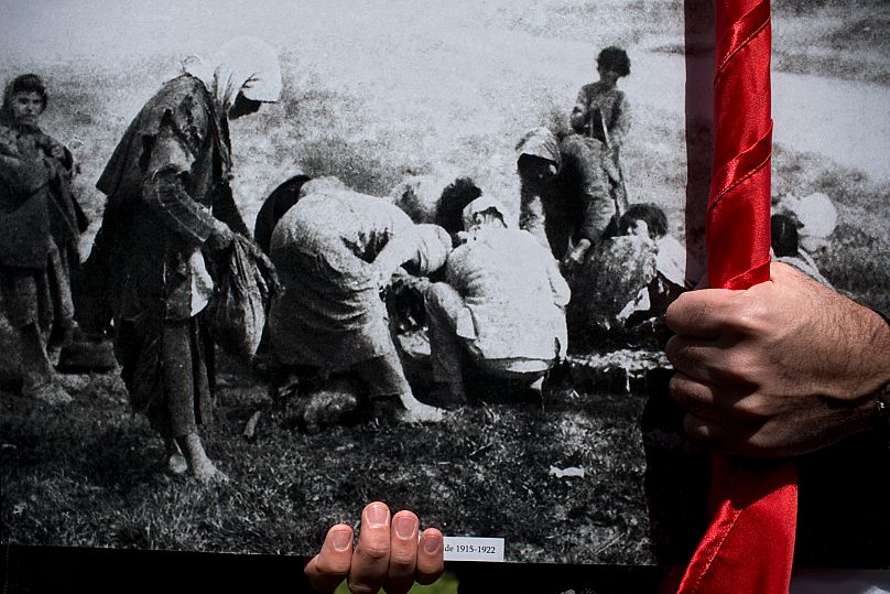 An Armenian man holds an image from the Armenian genocide during a ceremony to commemorate the 100th anniversary in Jerusalem, Israel, Friday, April 24, 2015.