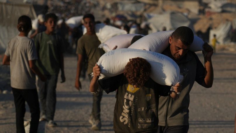 فلسطينيون يحملون أكياس طحين حصلوا عليها من قافلة مساعدات إنسانية وصلت إلى مدينة غزة، الأحد 24 أغسطس 2025.