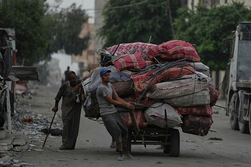 Displaced Palestinians fleeing Jabaliya move with their belongings on a street in Gaza City, 26 August, 2025