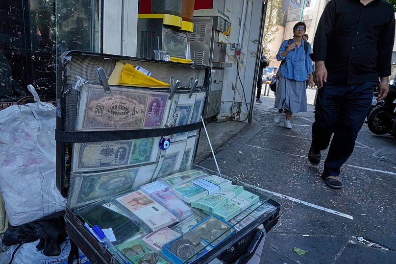 Current and pre-revolution Iranian banknotes are displayed by a street money exchanger in downtown Tehran, 28 August, 2025