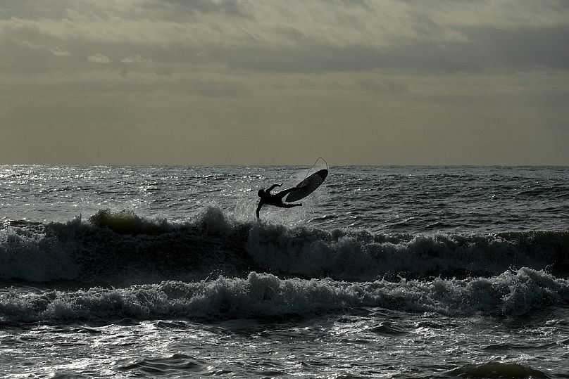 A surfer rides a wave at Rome's Ostia beach, 21 November, 2024