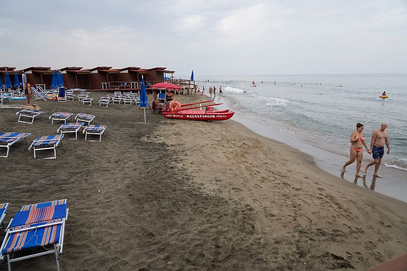 People stroll on the beach at the Venezia establishment in Ostia, 16 August, 2024