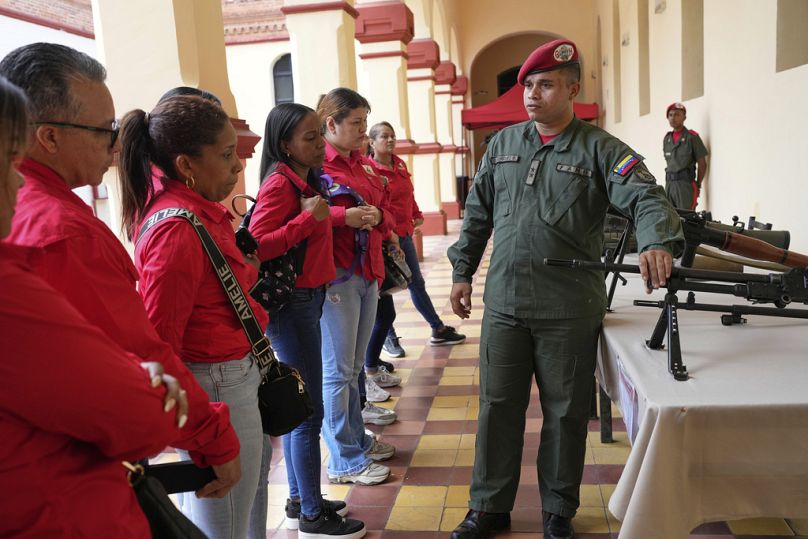 عضو في الحرس الرئاسي يعرض أسلحة لأشخاص سجلوا للانضمام إلى الميليشيات المدنية خلال حملة تجنيد وطنية في المتحف العسكري بكاراكاس، فنزويلا، السبت 23 أغسطس 2025.