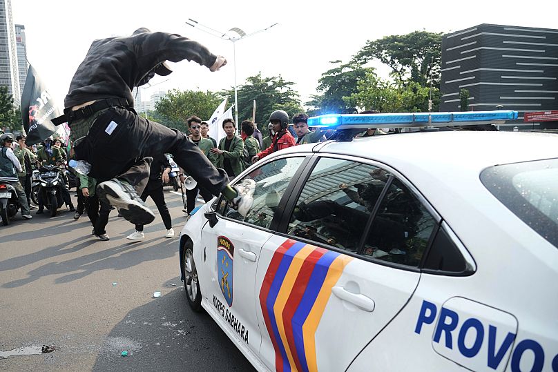 A student attacks a police car during a protest following the death of a delivery rider in Jakarta, 29 August, 2025