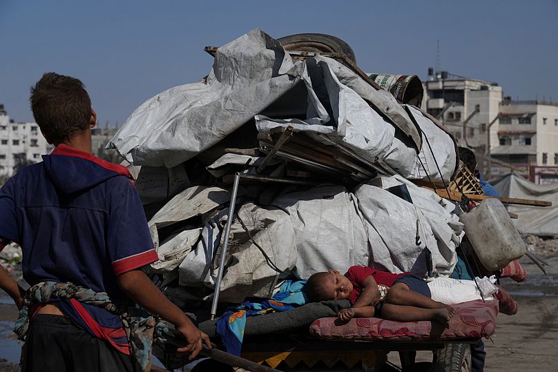 Un bambino palestinese di 3 anni dorme su un carro trainato da cavalli mentre la sua famiglia sfollata fugge dal nord della Striscia di Gaza, trasportando i propri averi su un