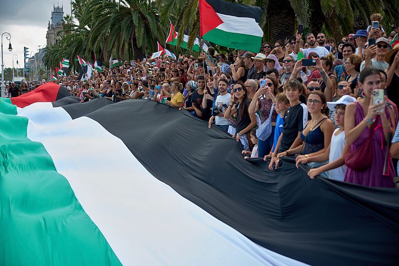 People hold Palestinian flags as they bid farewell to activists setting sail to join a civilian flotilla bound for Gaza, in Barcelona, Spain, on Sunday, August 31, 2025.