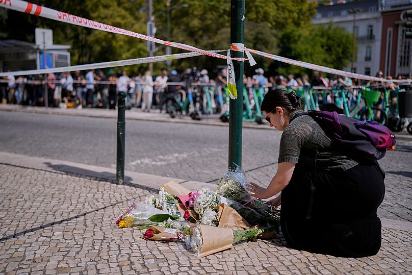 A woman places flowers at the site where a tourist streetcar derailed and crashed in Lisbon, 4 September, 2025