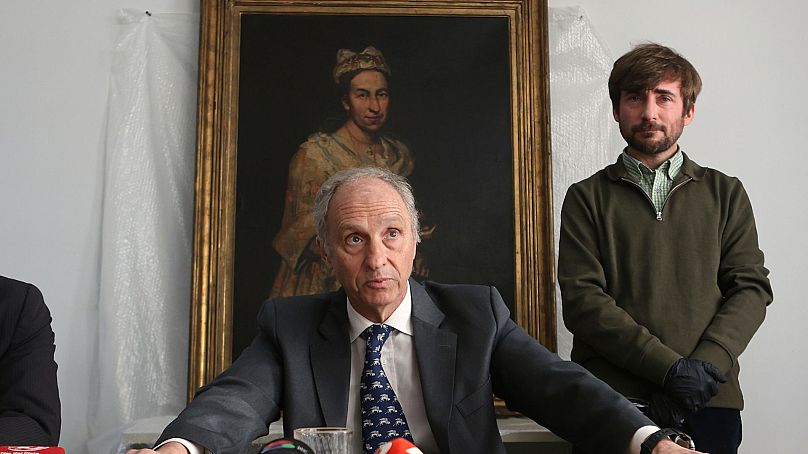 Прокурор Даниэль Адлерс дает пресс-конференцию. За ним картина Гисланди "Портрет дамы". 