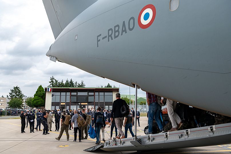 Personas desembarcan de un avión militar francés, al oeste de París, el 29 de agosto de 2021, tras ser evacuadas de Afganistán. 