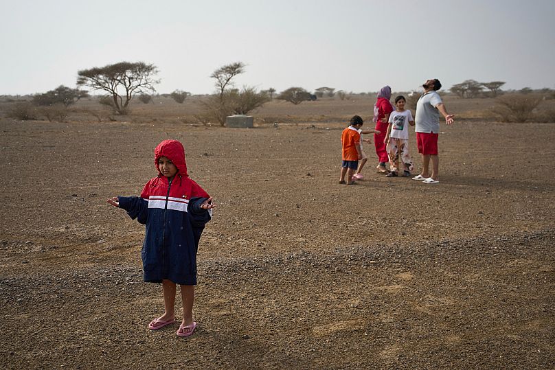 People stand in the rain as they chase rain showers in Fujairah, United Arab Emirates.