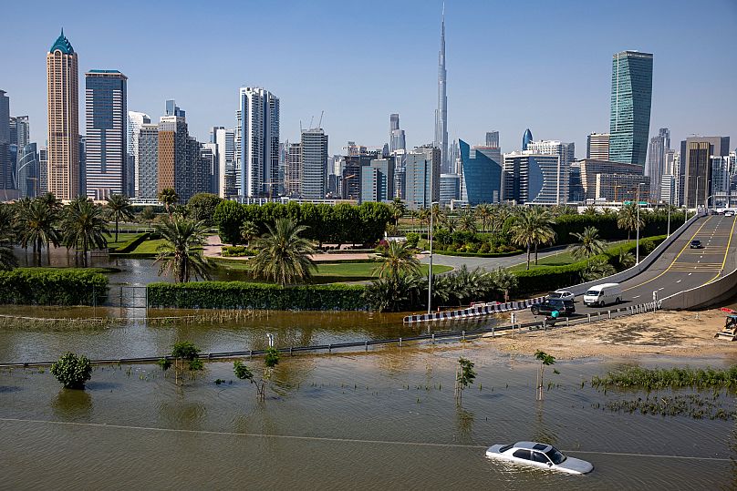 An abandoned vehicle stands in floodwater caused by heavy rain with the Burj Khalifa in the background in April 2024. 