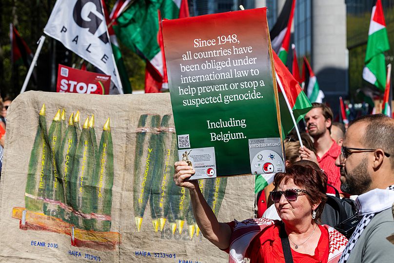 Uma mulher segura um cartaz enquanto marcha durante a manifestação da Linha Vermelha para Gaza no centro de Bruxelas, domingo, 7 de setembro de 2025. 