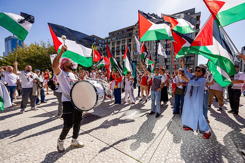 As pessoas agitam bandeiras palestinianas enquanto participam na marcha da Linha Vermelha para Gaza no centro de Bruxelas, domingo, 7 de setembro de 2025. 