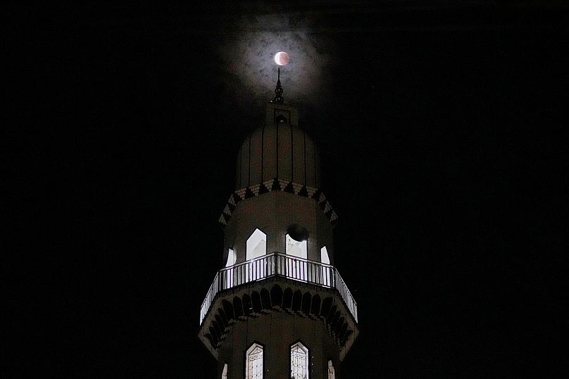O eclipse lunar visto através do minarete de uma mesquita em Rawalpindi, no Paquistão, 8 de setembro de 2025.