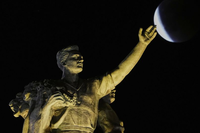 La luna llena sale detrás de una escultura situada en lo alto del pabellón central del VDNKh durante un eclipse lunar total el domingo 7 de septiembre de 2025. 