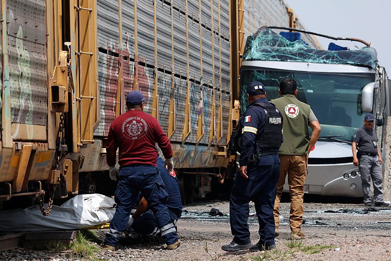 Les secouristes évacuent un corps sur les lieux d'un accident mortel où un train de marchandises a percuté un bus à deux étages à Atlacomulco, au Mexique