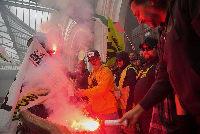 A railway worker holds a smoke bomb during 'Block Everything' demonstrations inside the Gare de Lyon train station in Paris, Wednesday 10 September.