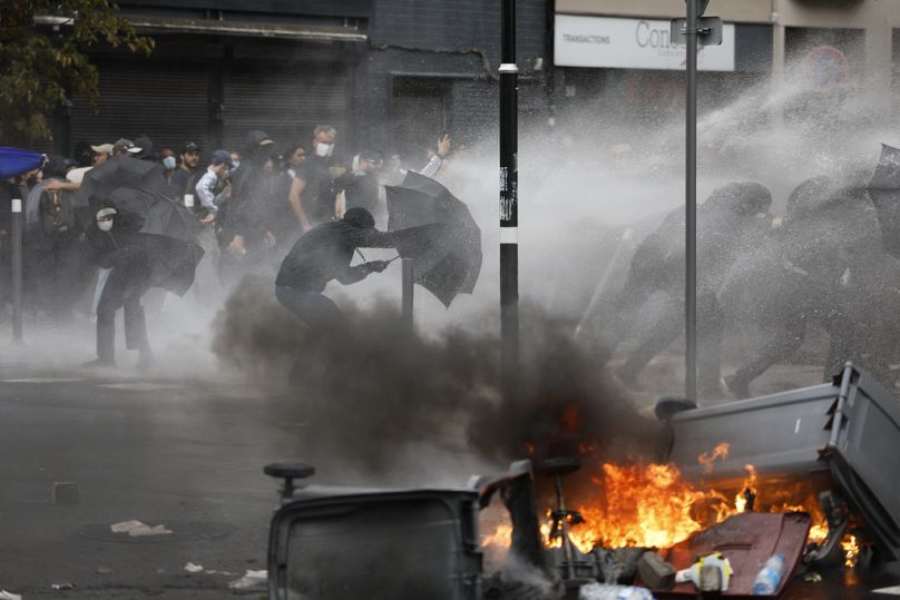 Manifestantes protegem-se de um canhão de água atrás de guarda-chuvas em Lille, norte da França.