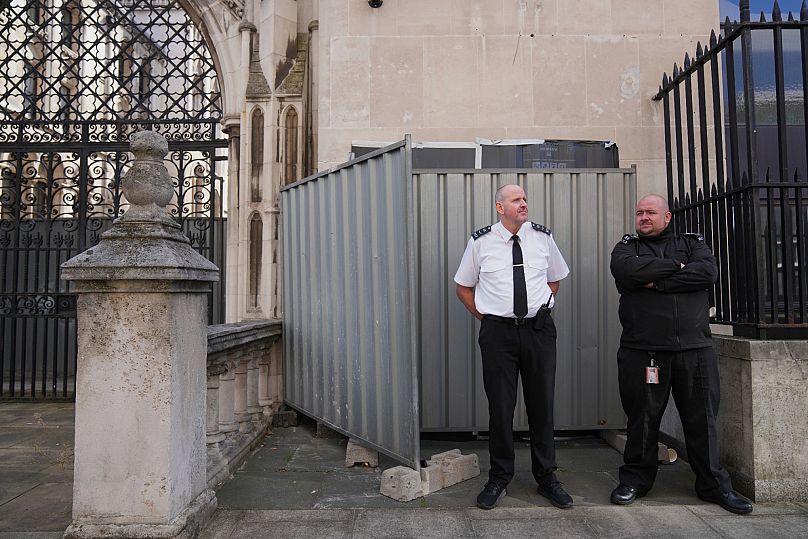 Security officials stand in front of large sheets of black plastic and two metal barriers which conceal street artist Banksy's latest artwork