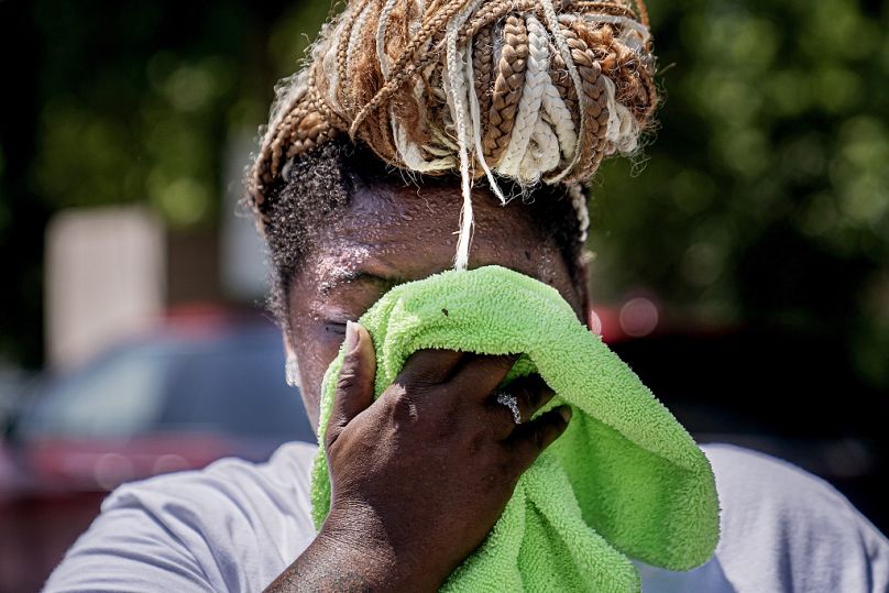 FILE - Nicole Brown wipes sweat from her face while setting up her beverage stand near the National Mall on July 22, 2022, in Washington.