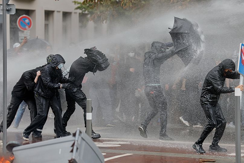 Protesters of the "Block Everything" movement take cover from a spraying water canon in Lille, 10 September 2025