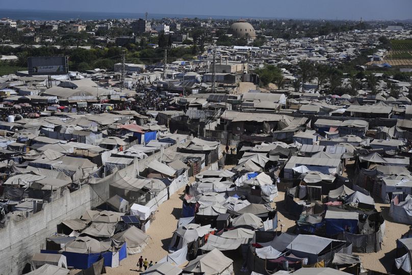 Palestinesi sfollati attraversano un campo di tende a Muwasi, un'area che Israele ha designato come zona sicura, a Khan Younis, nel sud della Striscia di Gaza, mercoledì 10 settembre 2025.