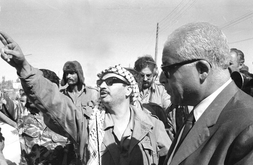 ياسر عرفات يلوح بإشارة السلام مع رئيس وزراء تونس في إربد، 5 أكتوبر 1970، بعد اتفاق لسحب المسلحين من شمال الأردن
