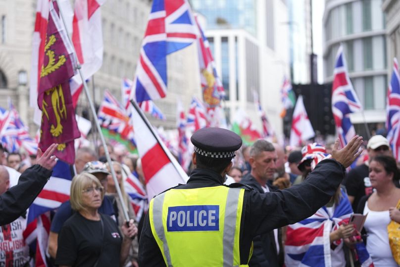 A police officer stands in front of demonstrators taking part in a Tommy Robinson-led Unite the Kingdom march and rally, in London, Saturday Sept. 13, 2025.