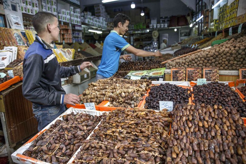 In this Sunday, May 20, 2018 photo, customers pick dates to buy for the holy month of Ramadan in the central market in the medina of Rabat, Morocco.